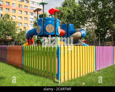 Bucharest/Romania - 06.22.2020: Small children;s park between apartment blocks surrounded with colored wooden fence. Stock Photo