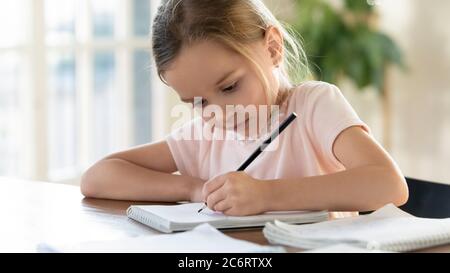 Close up focused little girl drawing with pencil in notebook Stock Photo