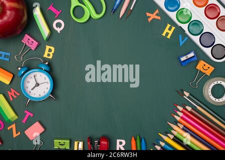 Back to school shopping concept. Top above overhead view photo of colorful stationery and an apple isolated on greenboard Stock Photo