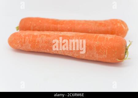 Raw carrots against a white background, with a shallow depth of field Stock Photo