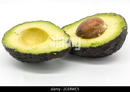 A halved avocado with stone in-situ, against a white background Stock Photo