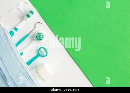 Teeth dental care instruments, face mask on white green background Stock Photo