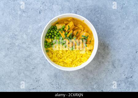 Take Away Indian Street Food Tikka Masala with Chicken, Curry Basmati Rice, Green Peas and Coconut Milk Sauce in Plastic Container Bowl. Stock Photo