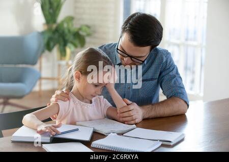 Caring father helping upset little daughter with school homework Stock Photo