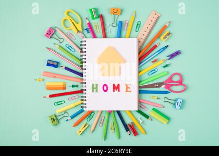 Studying at home concept. Top above overhead view photo of colorful stationery and blank notebook with house shaped paper and home letters on top isol Stock Photo