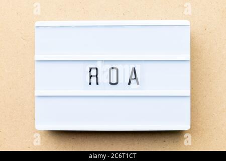 White lightbox with word ROA (Abbbreviation of Return on assets) on wood background Stock Photo