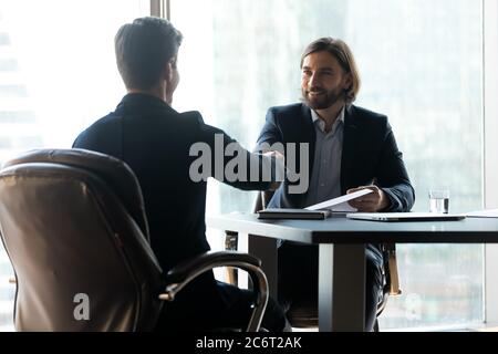 Two smiling young businessmen establishing partnership at meeting. Stock Photo