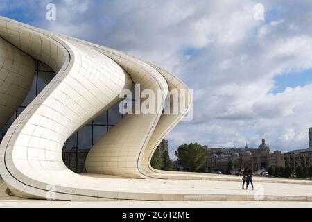 Two teenage girls running up the front of the Heydar Aliyev center, designed by Zaha Hadid the centerpiece of modern architecture in Baku Azerbaijan Stock Photo