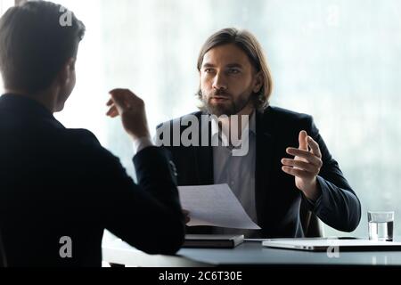 Serious young executive manager discussing contract with partner. Stock Photo