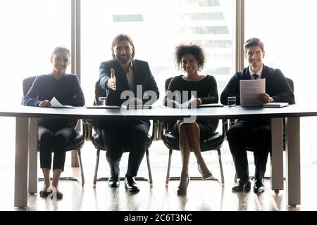 Group of happy young mixed race managers welcoming job candidate. Stock Photo