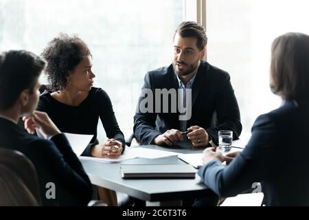 Focused mixed race employees listening to team leader. Stock Photo