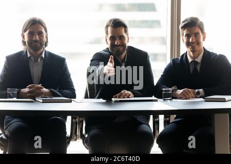 Smiling friendly young male hr managers stretching hand for welcoming. Stock Photo