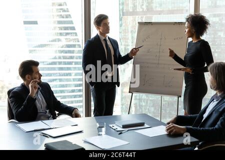 Two young mixed race speakers presenting corporate marketing strategy. Stock Photo