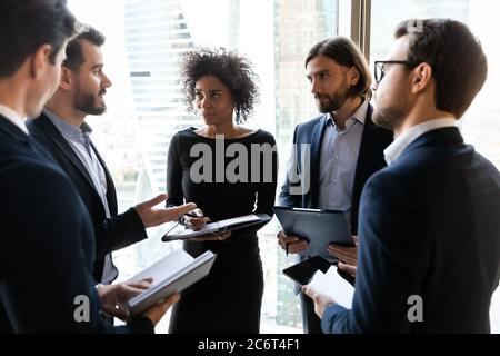 Focused young diverse business people discussing project ideas in circle. Stock Photo
