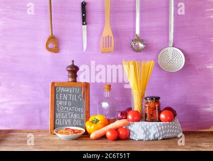 Italian food, ingredients for spaghetti dish with vegetables, red lentils and sun-dried tomatoes, recipe written on kitchen black board Stock Photo