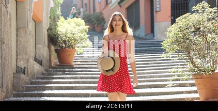 Happy travel tourist woman going downstairs in Bellagio on Lake Como, Italy. Girl on summer vacation visiting famous tourist destination in Europe. Stock Photo