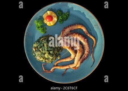 Balkan cuisine. Dish with grilled octopus with chard leaves ( blitva ) and potatoes, isolated on black background. Flat lay Stock Photo