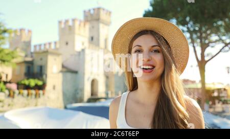 Portrait of smiling tourist woman with Sirmione Castle on the background, Lake Garda, Italy Stock Photo