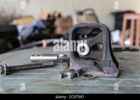 Old rubber engine mount with tools on the table background. Stock Photo