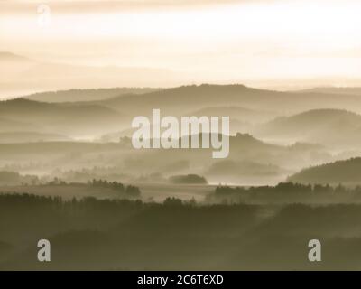 The sun shines against the white mist floating above top of the hill. Stock Photo