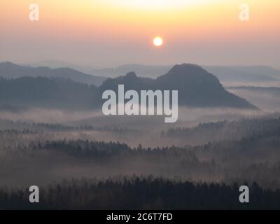The sun shines against the white mist floating above top of the hill. Stock Photo