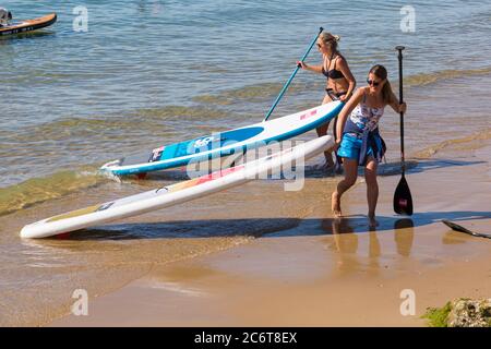 Poole, Dorset UK. 12th July 2020. UK weather: very warm sunny day at Poole beaches as temperatures rise and sunseekers head to the seaside to enjoy the sunshine. Paddleboarders return to shore. Credit: Carolyn Jenkins/Alamy Live News Stock Photo