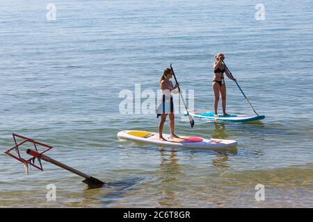 Poole, Dorset UK. 12th July 2020. UK weather: very warm sunny day at Poole beaches as temperatures rise and sunseekers head to the seaside to enjoy the sunshine. Paddleboarders.  Credit: Carolyn Jenkins/Alamy Live News Stock Photo