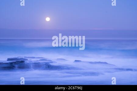 The wave crashing rocks in Garie Beach under moonlight Stock Photo