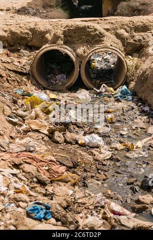 An open sewer filled with rubbish by the side of a dirt alley, Korogocho slum, Kenya, East Africa Stock Photo