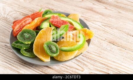 plate of dried fruits on a wooden table. kiwi, mango, papaya, melon, pineapple. do not affects blood sugar levels Stock Photo