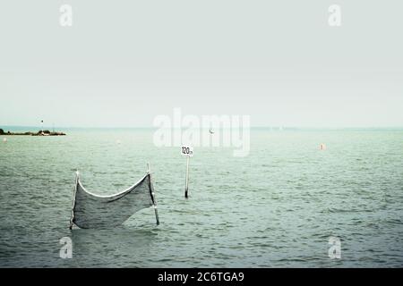 Caution sign and water volleyball court in the Lake Balaton. Minimalistic photo of a warning sign, water depth 120 cm and a net for background. Stock Photo