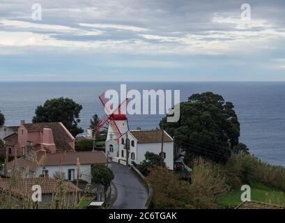 view on village Bretanha with old windmill called Red Peak Mill, Moinho do pico vermelho sea and clouds background, Sao Miguel, Azores Stock Photo