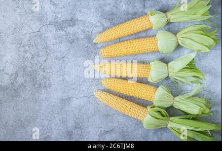 Sweet raw organic corn cobs with leaves ready to cooking on grill top view. Place for your text Stock Photo