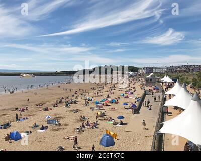 People enjoy the sunshine and warm weather on Whitmore Bay beach in Barry Island, South Wales. Stock Photo