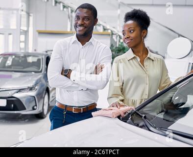 just imagine us on the road. portrait of happy african american couple checking out a car in modern dealership, they choose new car together Stock Photo