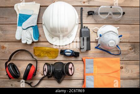 Work safety protection equipment flat lay. Industrial protective gear on wooden background. Construction site health and safety concept.