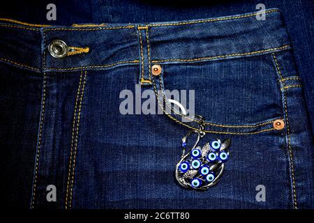 Close up of a pocket of blue jeans with a peacock key chain hanging out of it. Stock Photo