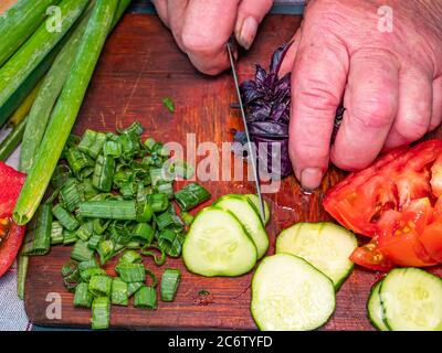 Slicing violet basil salad leaves with a knife on a cutting board. Stock Photo