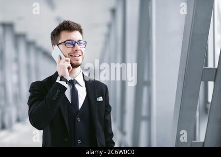 Smiling business man talking on smartphone wearing specs Stock Photo