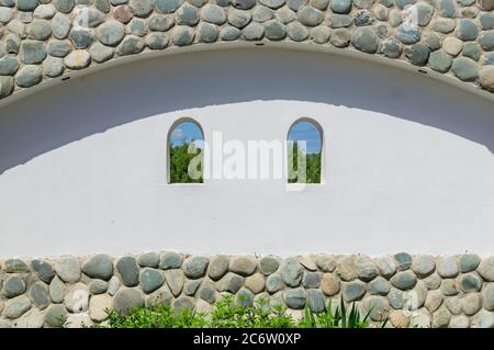 white wall decorated with stones with two windows viewing nature landscape Stock Photo
