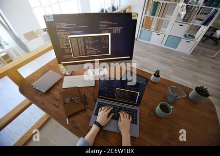 Wide angle above view at female hands typing on keyboard while coding at workplace in modern office interior, copy space Stock Photo