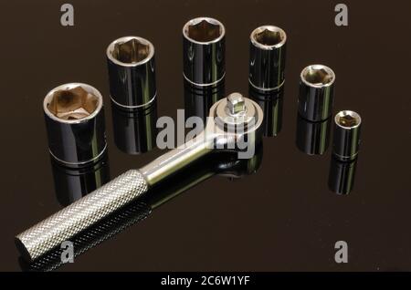 Shiny chrome six piece socket set tool on reflective black surface Stock Photo