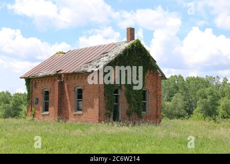 an abandoned overgrown brick old school house building Stock Photo