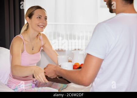 The husband brought his wife breakfast in bed. A young woman is having breakfast in bed. Stock Photo
