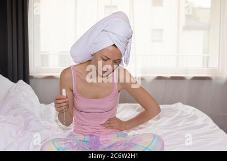 A young woman experiences severe menstrual pain. Stock Photo