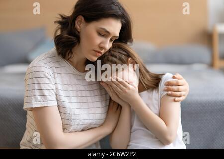 Mother is feeling sorry for a crying child. Mum is hugging her daughter. Stock Photo