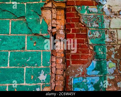 Semi-destroyed contact of two walls of different sizes of bricks Stock Photo