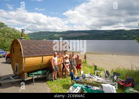 Loch Venachar, Loch Lomond and Trossachs National Park, Scotland, UK. 12th July, 2020. Pictured: Glasgow locals have made their own Sauna. What do you do in lockdown when the day spa is closed? Bring your own bespoke mobile sauna and bring it to a beautiful picturesque Scottish loch, which makes the perfect plunge pool to cool you down after a hot sizzling and relaxing loch-side sauna whilst enjoying a cool drink and some food. Credit: Colin Fisher/Alamy Live News Stock Photo