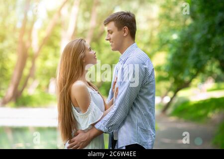 Carefree millennial couple embracing and looking at each other outdoors Stock Photo