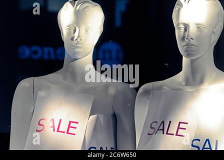 Retail sale sign attached to two mannequins in a storefront window Stock Photo